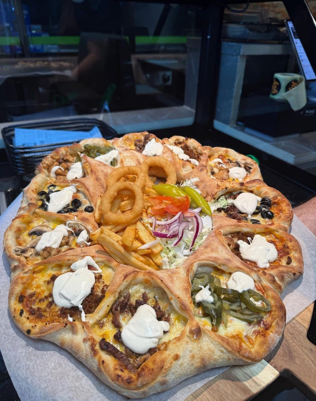Stor delepizza med ulike fyll, fries, løkringer og salat i midten fra JAFS Larvik